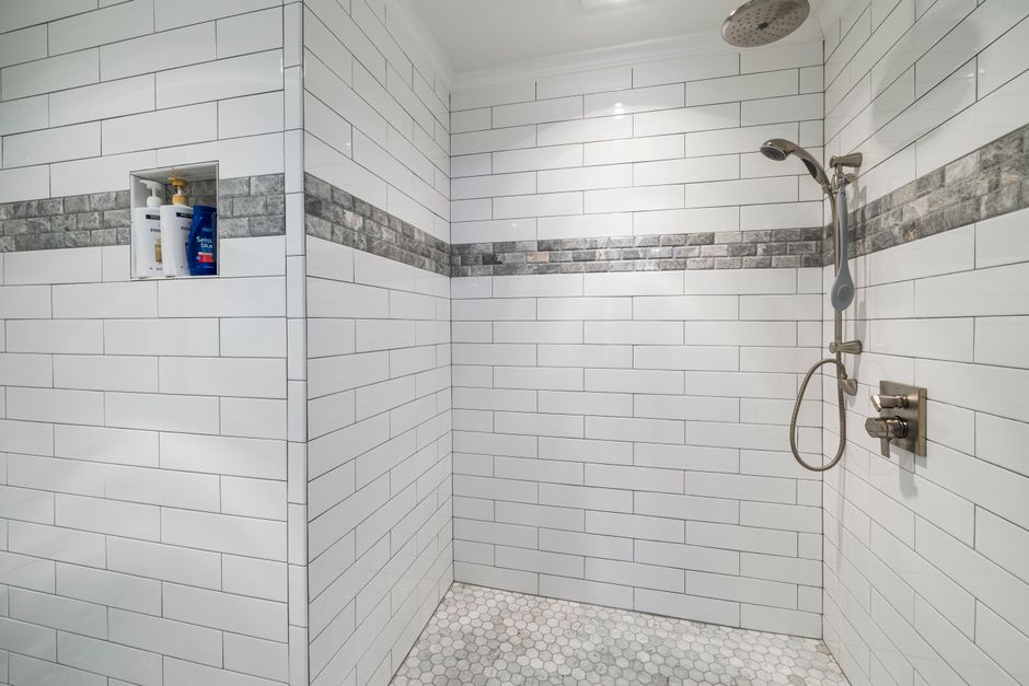 A bathroom under demolition with exposed wall framing and stripped shower area revealing underlying conditions.