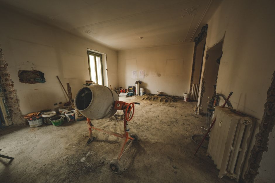 Interior renovation scene with exposed wall studs and visible plumbing or electrical lines after demolition.