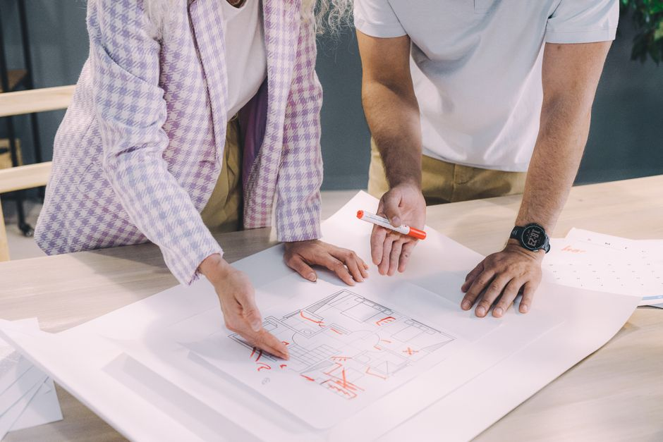 Homeowners and a contractor reviewing renovation plans and documents together at a table.