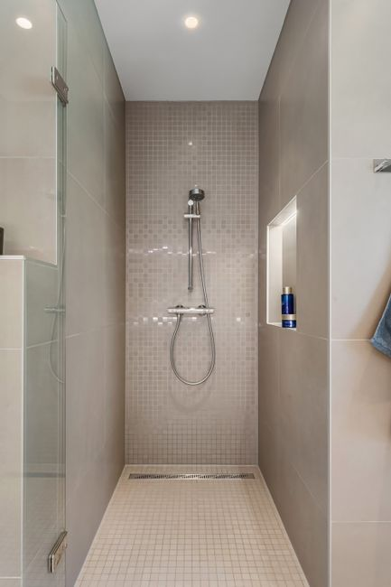 A worker installing tile in a shower area during a bathroom remodel.