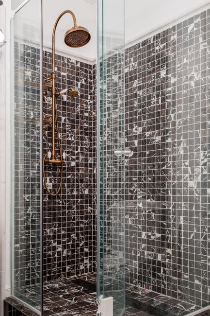 Frameless glass shower enclosure with visible water spotting on the glass surface.