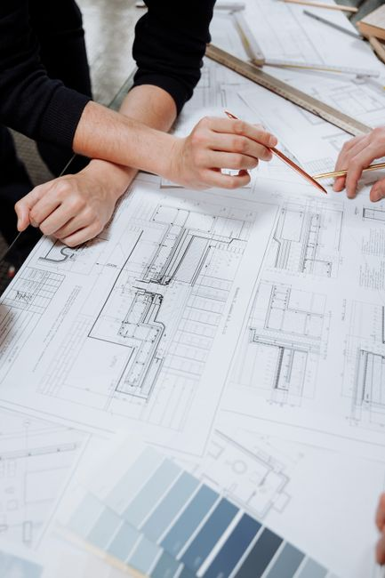 An architect or builder reviewing residential plans and site documents during a project planning meeting.