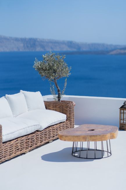 A discreet stone boutique hotel with sheltered outdoor seating, mature landscaping, and private terraces in a Greek island setting.