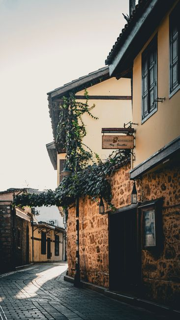 A charming Greek island town street near boutique hotels, with tavernas and evening foot traffic.