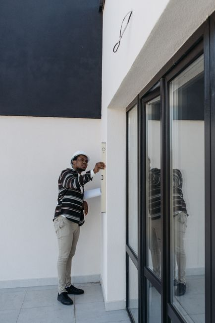 A contractor measuring an existing window opening inside a home before replacement.