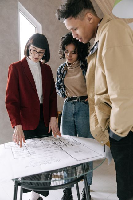 Homeowners reviewing renovation plans and floor layouts with a contractor at a table.