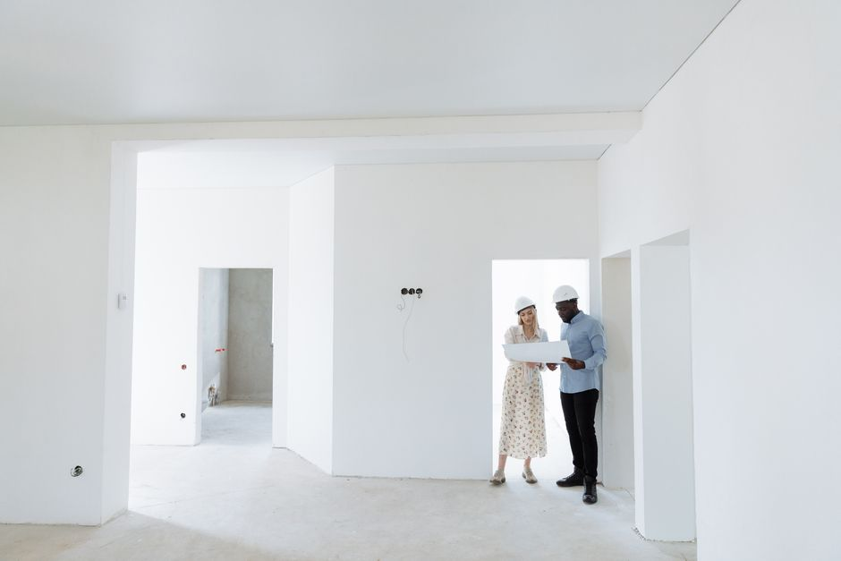 Homeowners reviewing kitchen renovation plans with a contractor at a table.