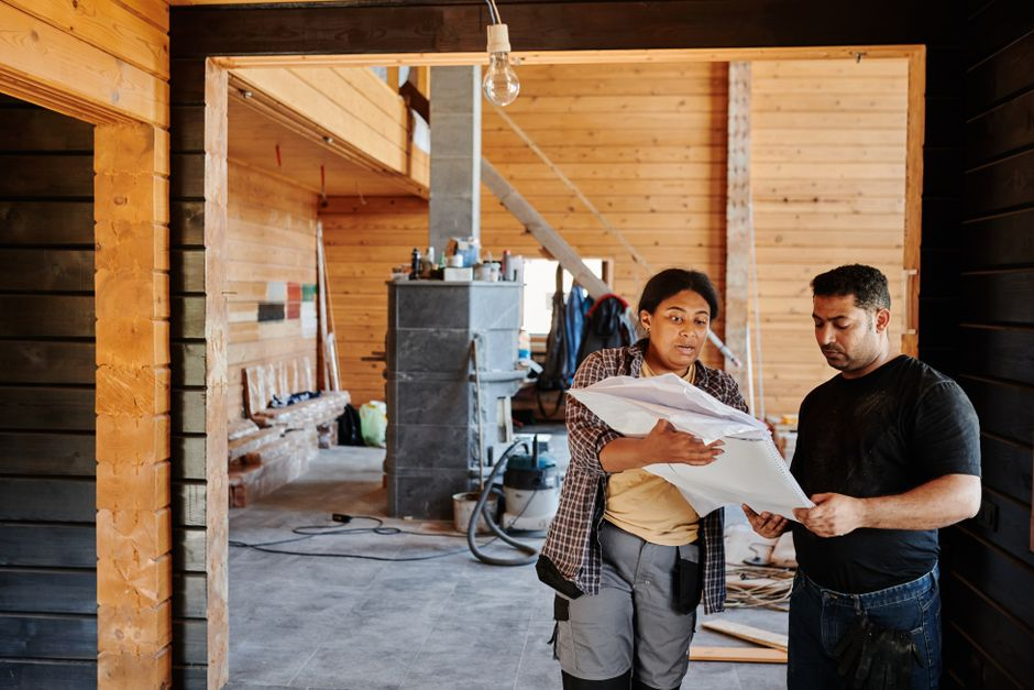 Contractor and homeowners discussing renovation drawings and construction logistics.