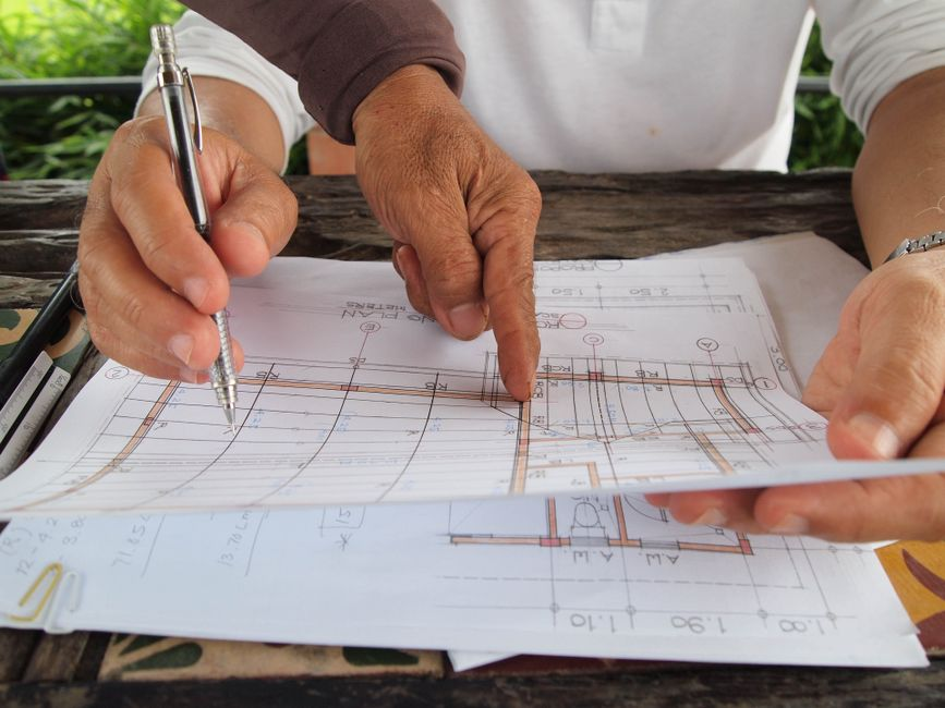 Blueprints, cost notes, and a calculator laid out during a home budget planning session.
