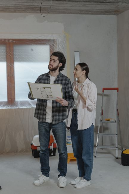 Homeowners reviewing renovation plans and drawings with a contractor at a table.