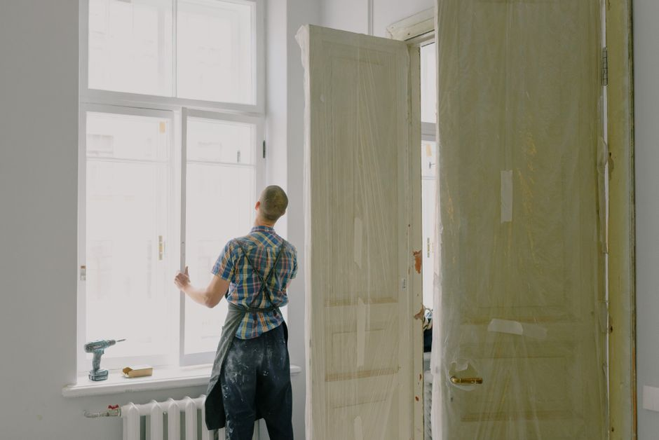 Installer working on a residential window opening, sealing the frame and checking fit during installation.
