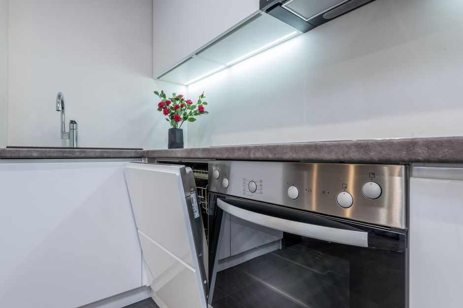 A kitchen with an open dishwasher door and a narrow walkway that interrupts movement through the space.