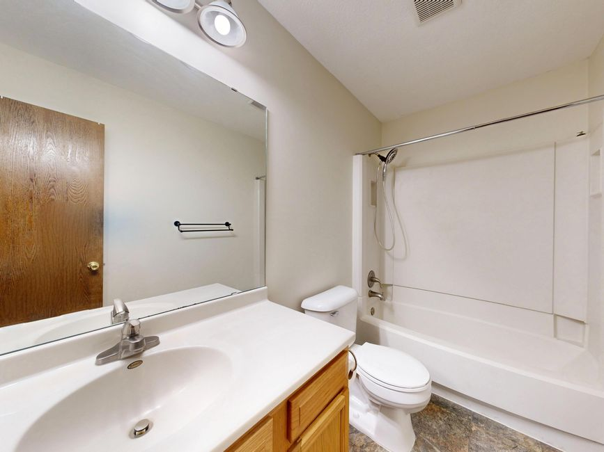 Plumber working on exposed supply and drain lines in a bathroom with walls open during renovation.