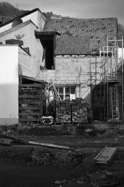 A house undergoing a second-story addition with upper-level framing and roof work visible.