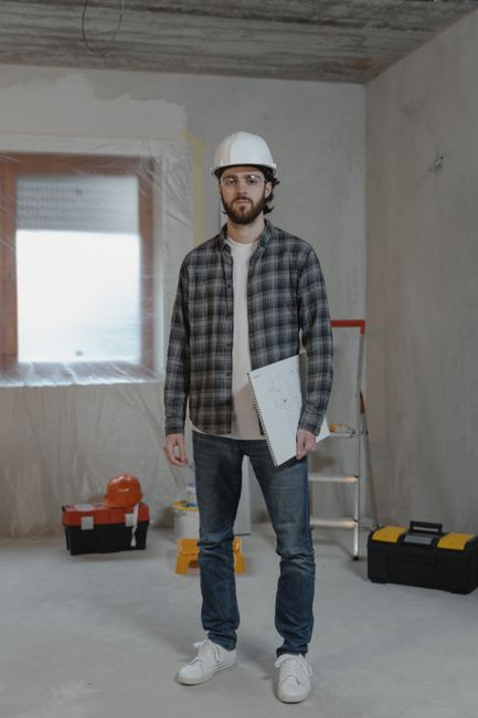 A contractor and homeowner reviewing house plans and measurements during an early renovation planning meeting.