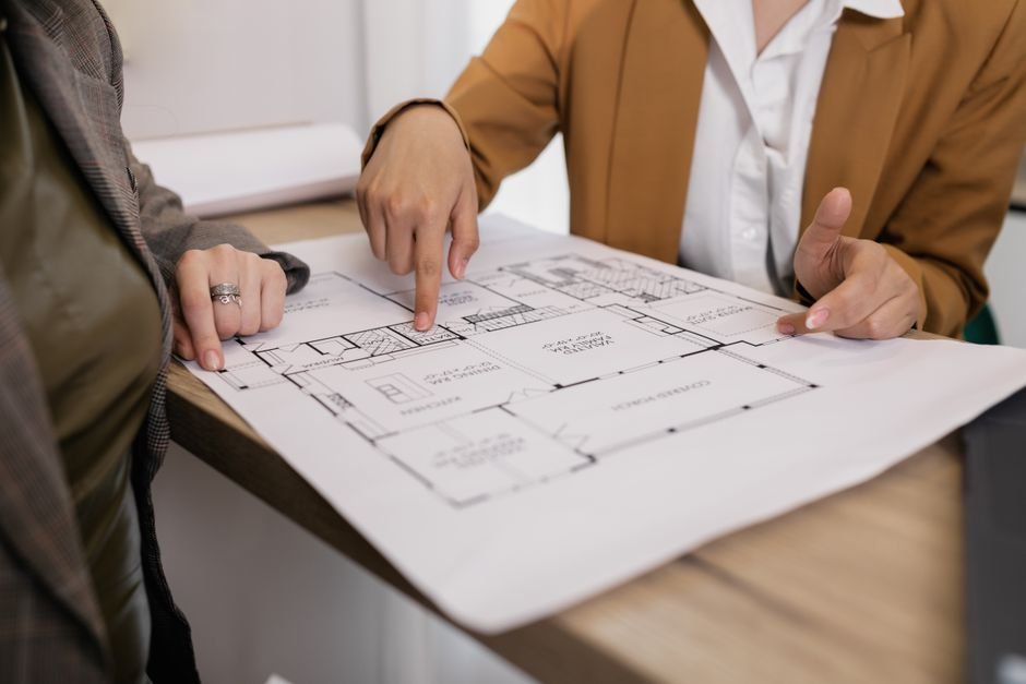 Homeowners reviewing renovation plans and blueprints with a contractor at a table.
