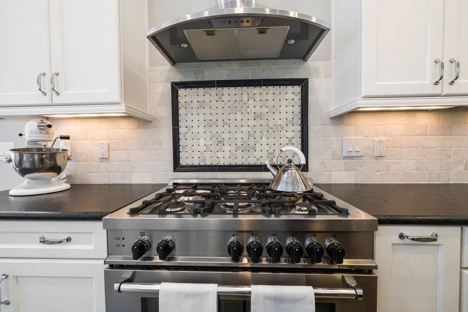 A renovated modern kitchen with an induction cooktop, cabinetry, and a vent hood.