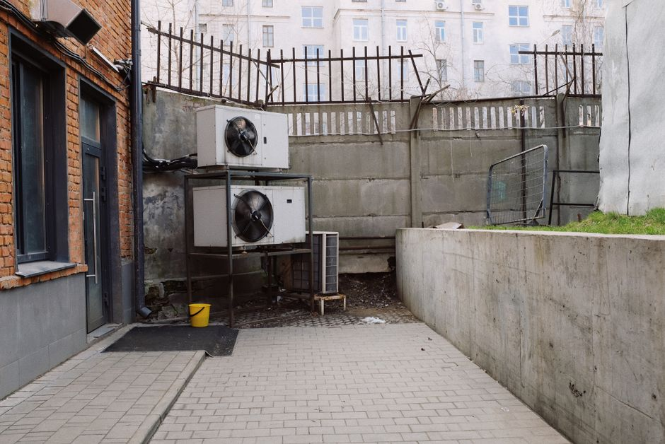 A residential heat pump outside a home with a technician inspecting nearby systems.