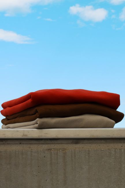 Several fabric swatches hanging side by side, showing differences between soft drape and stiffer structure.