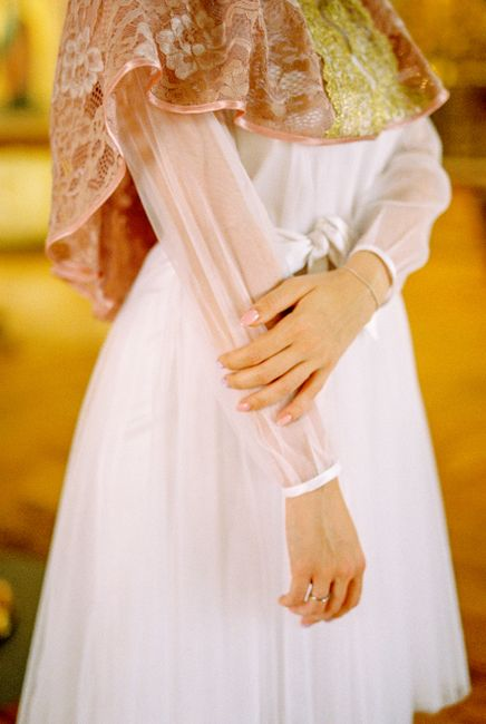 Close view of a wedding dress with soft chiffon sleeves and a flowing sheer overlay.