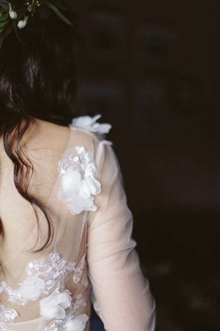 Detailed bridal lace sleeve and illusion back with floral embroidery over sheer fabric.