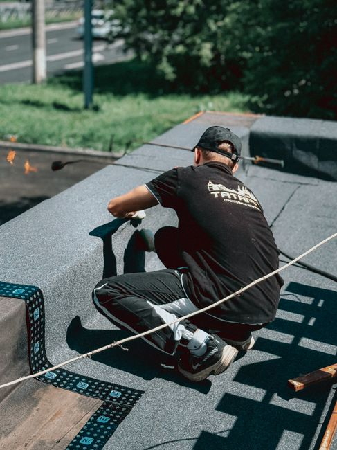Roofing crew coordinating materials and access on a commercial building with limited staging space.
