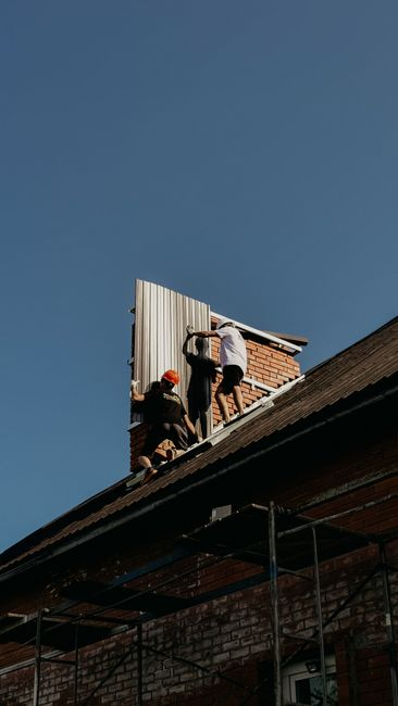 A roofer photographing exposed roof damage during a tear-off inspection.