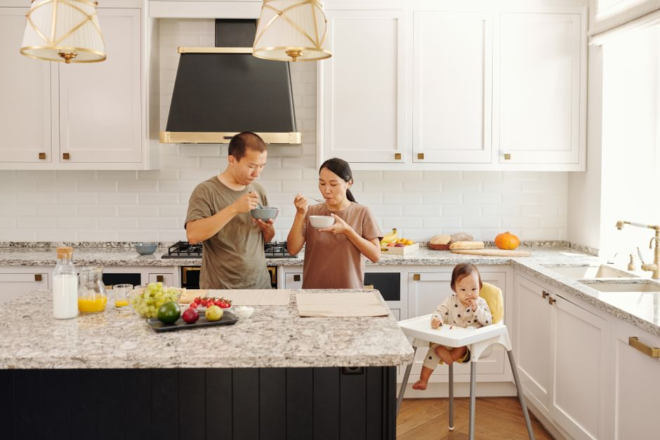 Two people using a kitchen at the same time, one at the sink and one preparing food at the counter.