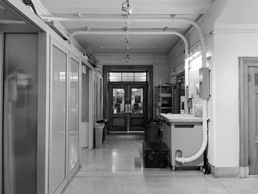Maintenance-access area with exposed utility pipes and overhead ceiling infrastructure in a commercial building.