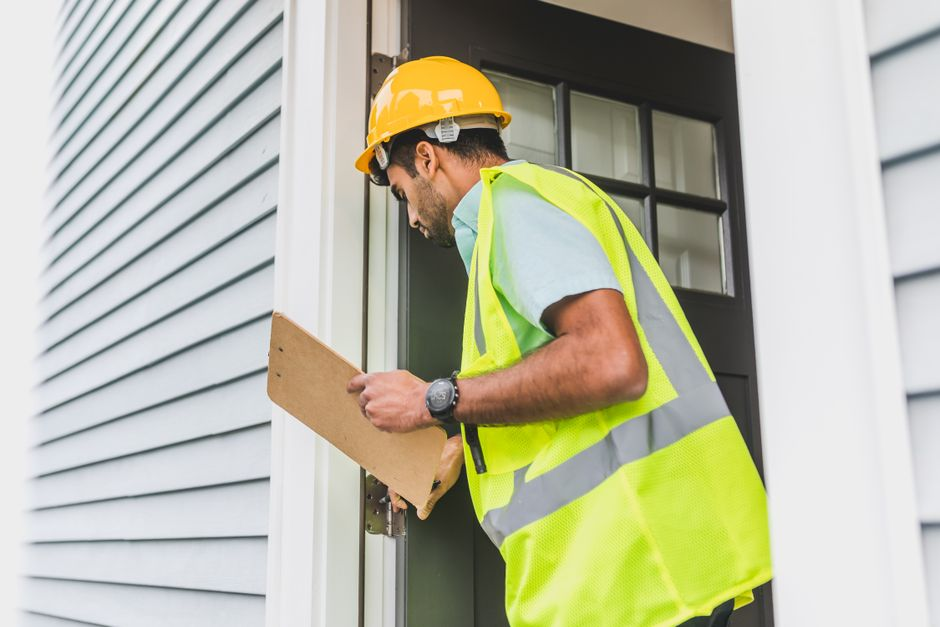 A contractor inspecting and measuring a residential backyard before planning construction.