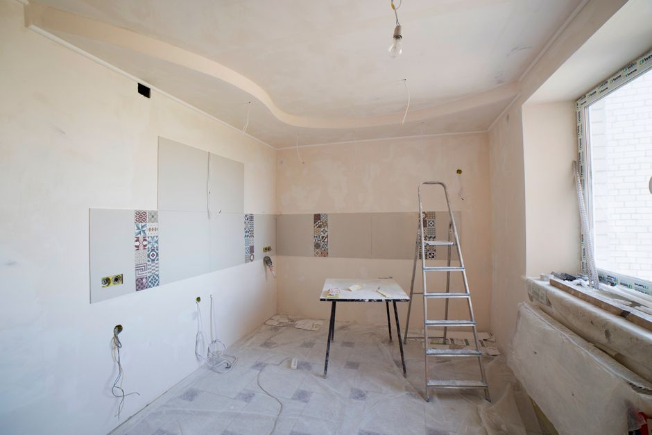 Close-up of a bathroom wall and baseboard showing water staining, peeling paint, and moisture damage.