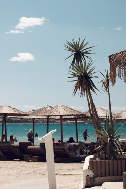 A peaceful Greek island beach with clear water, soft sun, and a relaxed late-summer atmosphere.