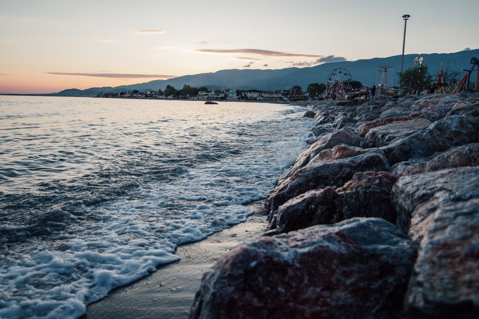 A broad beach with people strolling near the shore at sunset in a laid-back seaside town.