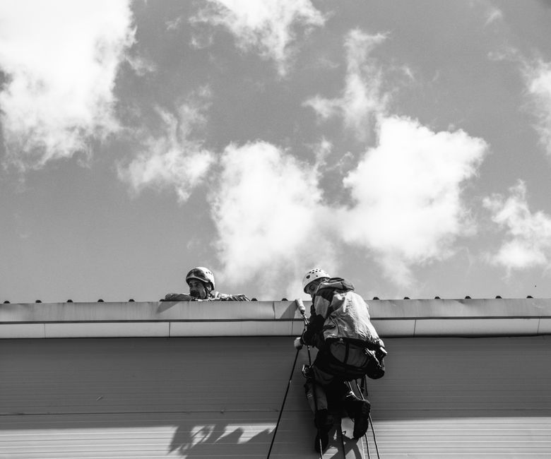 A pest control technician preparing to inspect a home attic using a ladder and protective gear.