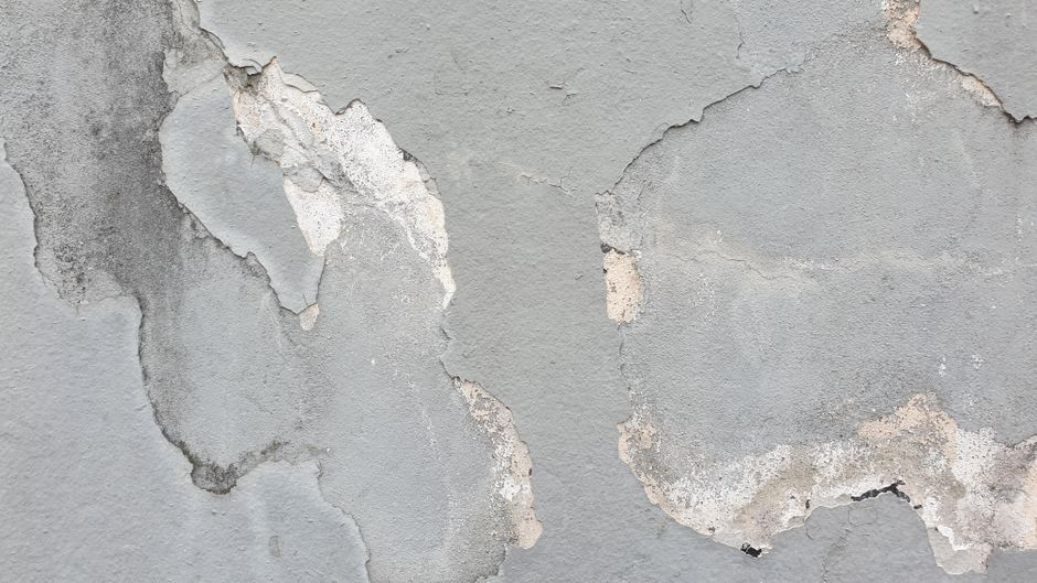 Subtle indoor moisture damage near a bathroom or window, with stained trim and baseboard swelling.