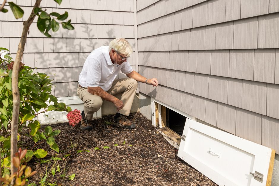 A homeowner or inspector using a flashlight to check a wall, trim, or baseboard for signs of moisture.