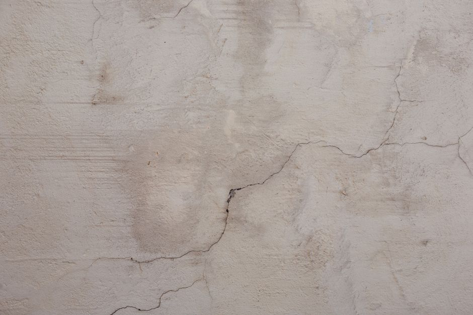 Interior ceiling with a visible water stain and damp drywall near a window after a storm.