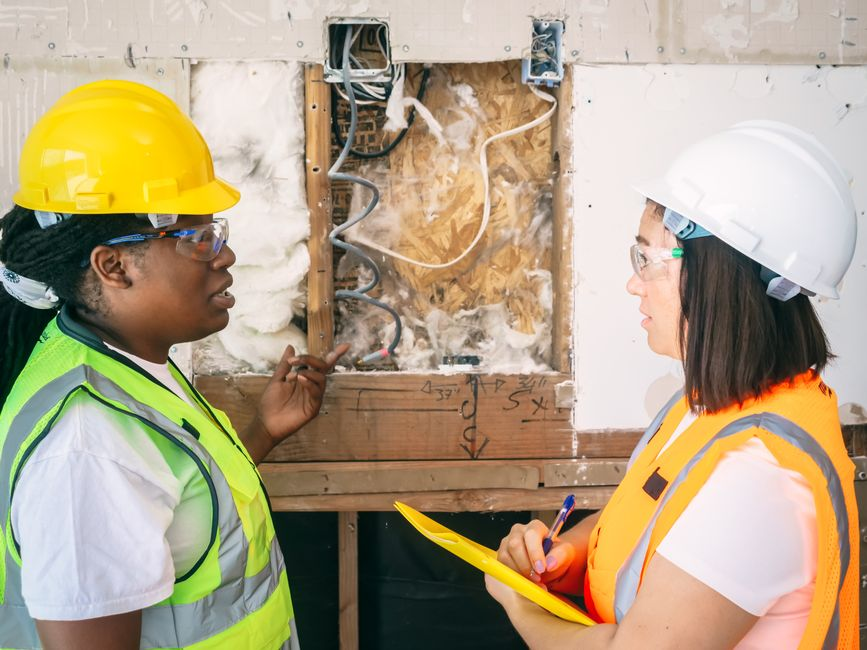 A restoration technician inspecting storm-related interior water damage and checking moisture levels in a home.