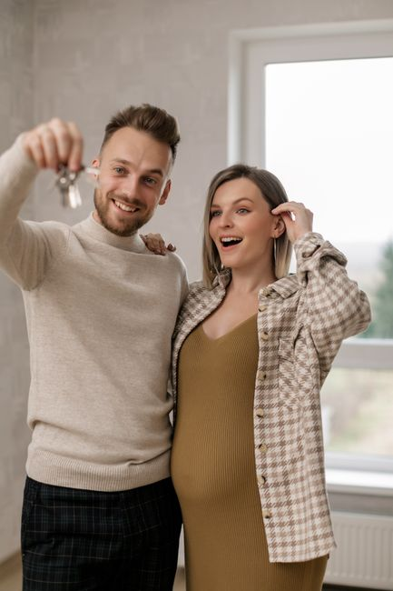 New homeowners holding keys inside a recently purchased house.