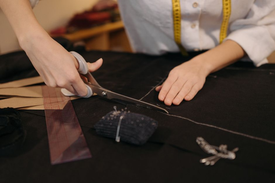 A sewing table with knit fabric being measured and cut for a garment project.
