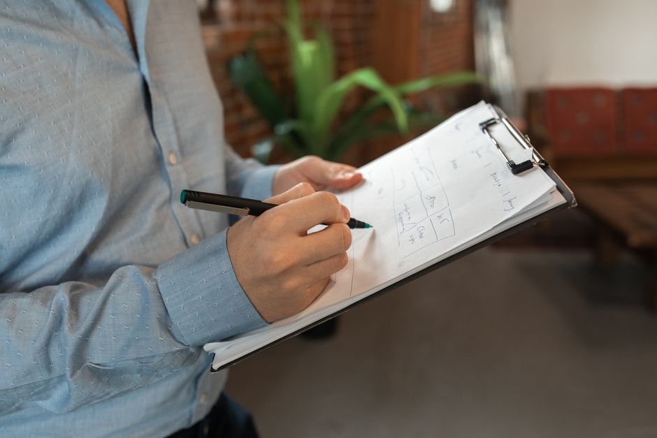 A buyer looking over a home inspection report and paperwork on a desk.