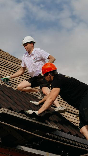 A roofing professional documenting roof problem areas with photos during an inspection.