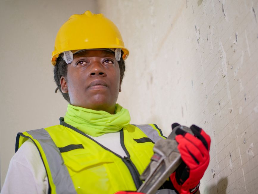 Restoration professional using a moisture meter during an indoor wall inspection.