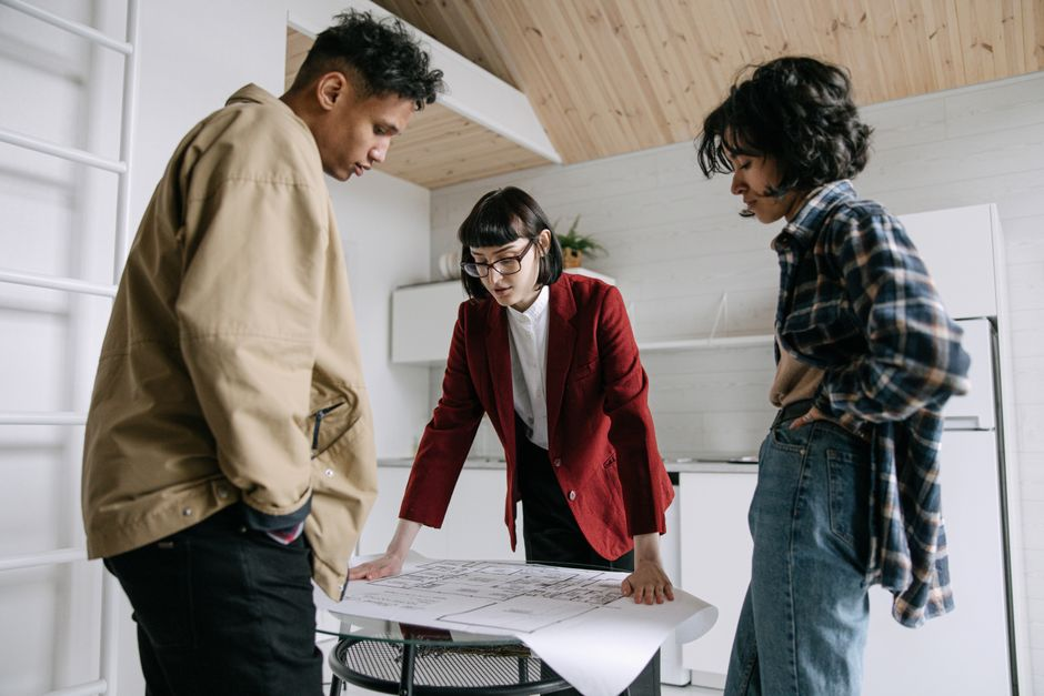 A contractor and homeowner reviewing bathroom renovation plans and measurements together.