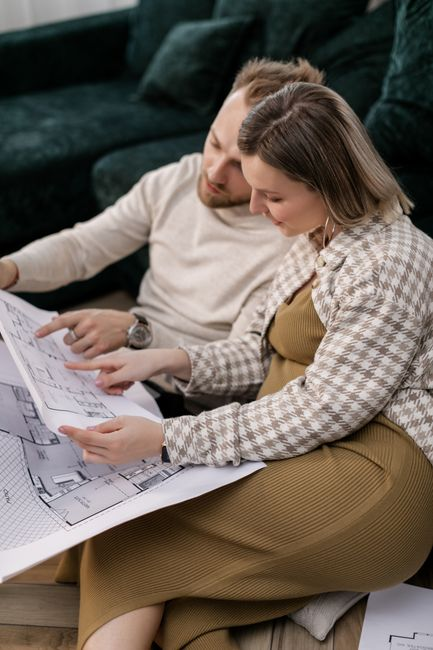 Homeowners reviewing renovation plans and drawings with a contractor at a table.