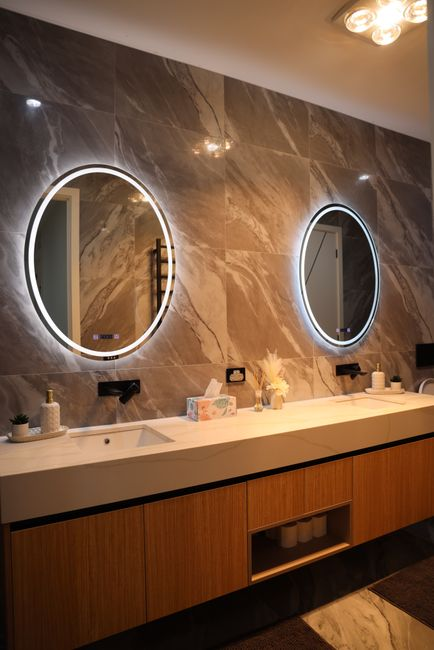 A modern bathroom vanity with flattering vertical mirror lighting and warm ambient illumination.