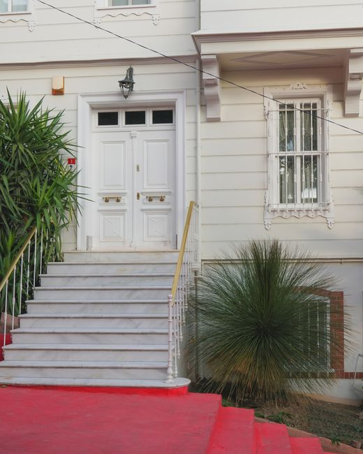 An older adult stepping carefully through a front door with a visible threshold and well-lit entry path.