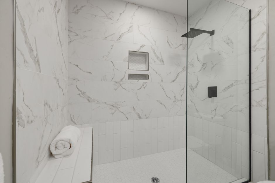 A modern curbless shower with a continuous floor, frameless glass, and subtle slope toward the drain.