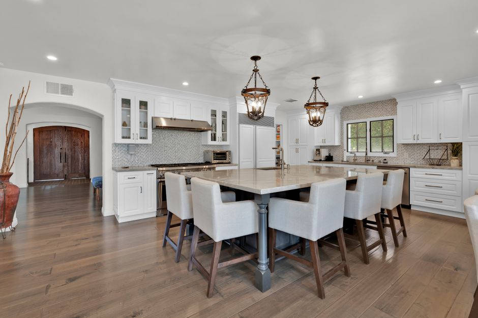 An expanded kitchen opened toward an adjacent dining area, showing a larger island and wider circulation space.