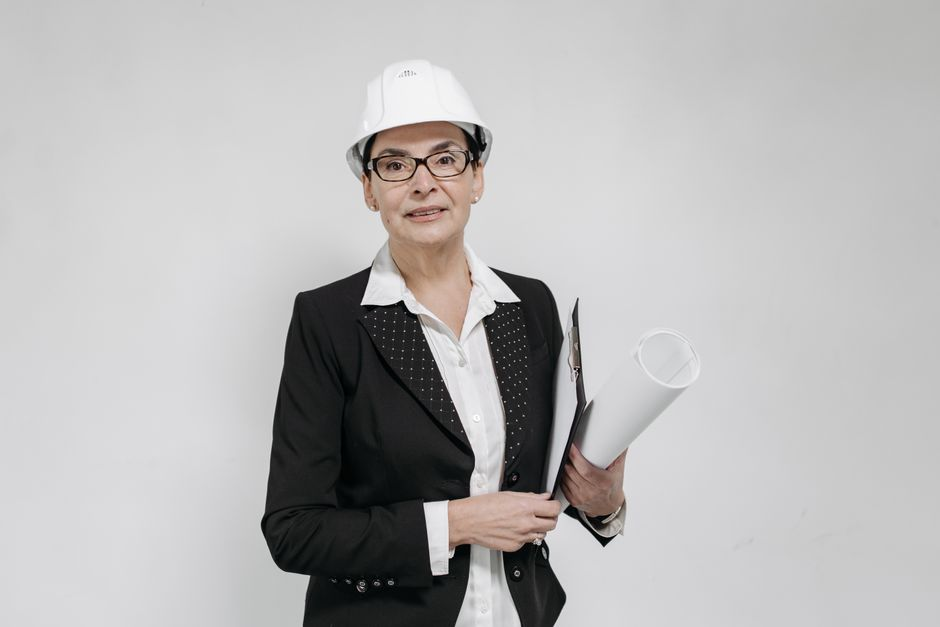 A contractor reviewing paperwork on a clipboard at a job site with a hard hat nearby.